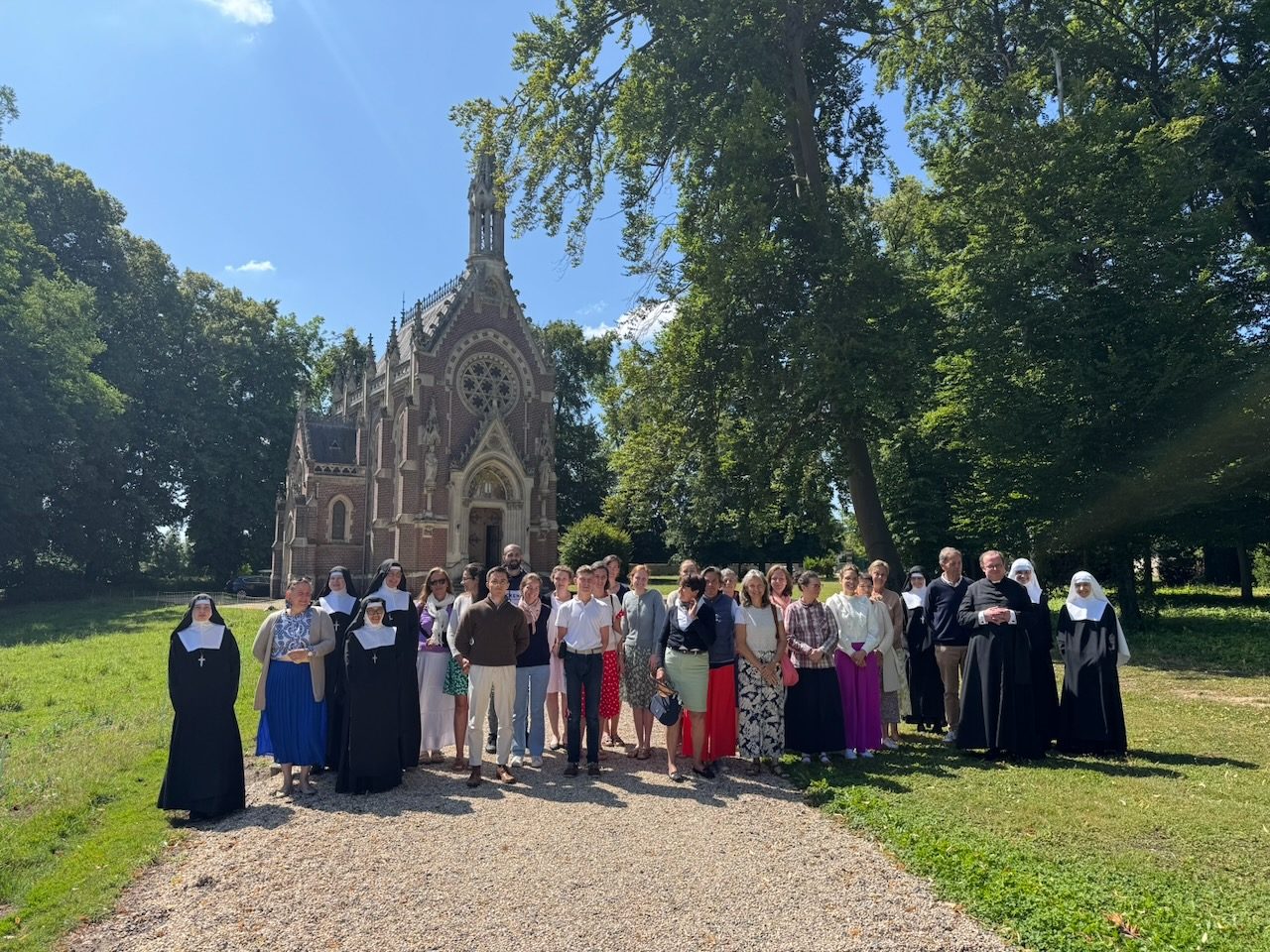 Un groupe de retraitants et de religieuses devant la chapelle néogothique